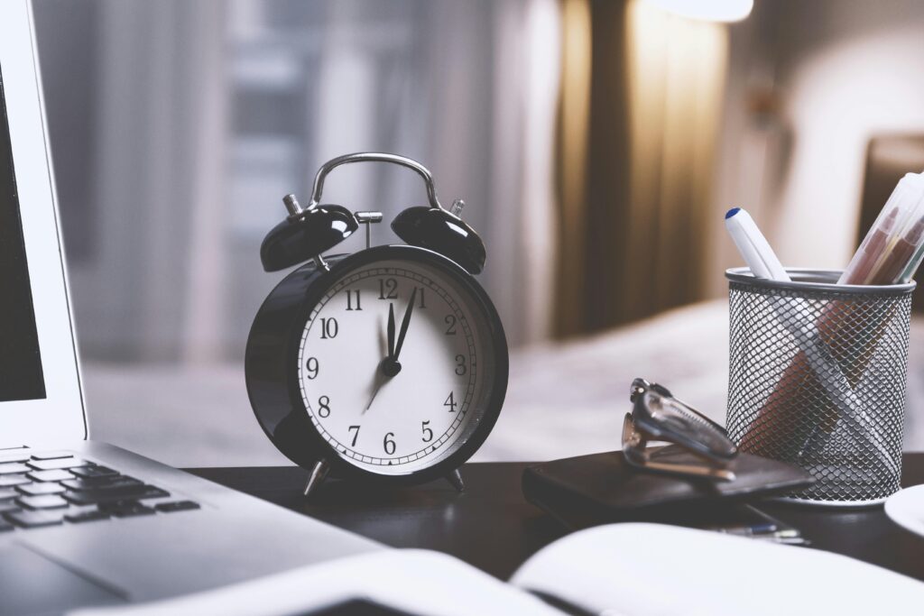 Reloj al lado de una laptop simbolizando el tiempo como recurso